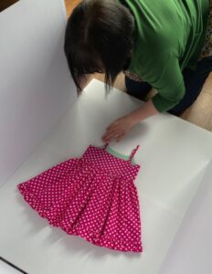 Laying out pink polkadot summer dress for flat lay photography